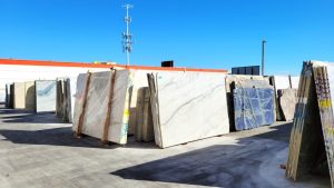 Outdoor slab yard at Paramount Quality Stone, showcasing marble, granite, and quartzite slabs under a clear blue sky.