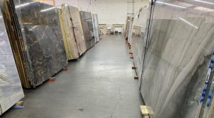 Interior view of Paramount Quality Stone slab warehouse and showroom, showcasing polished marble, granite, and quartzite slabs arranged in vertical racks.