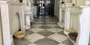 Paramount Quality Stone showroom interior featuring elegant marble fireplaces, decorative stone sinks, and a checkered marble floor.