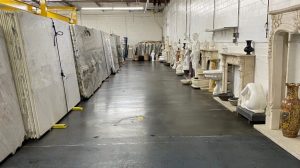 Paramount Quality Stone showroom featuring marble, granite, and quartzite slabs alongside an elegant display of carved stone statues, fireplaces, and decorative pieces.